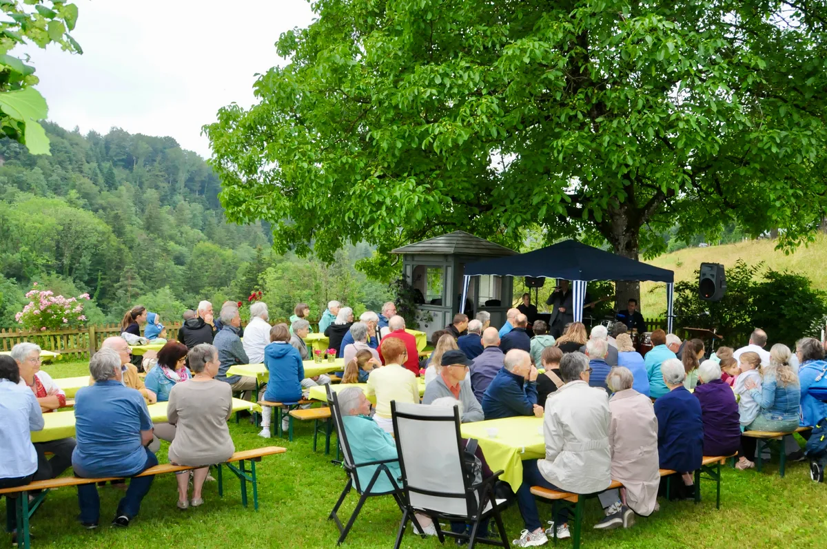 Man sieht Besucher draussen an einem Gottesdienst.
